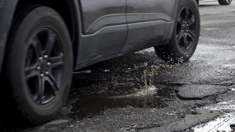 A black car navigating a pothole