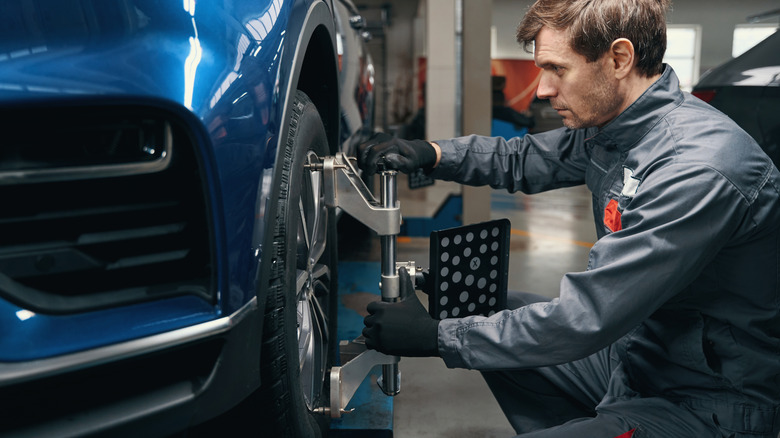 A man aligning the wheels of a blue car