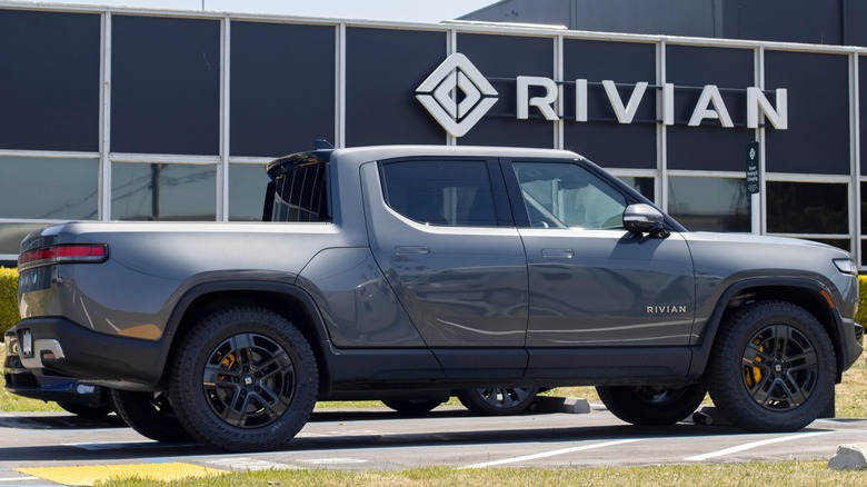 Rivian truck parked in front of a Rivian sign