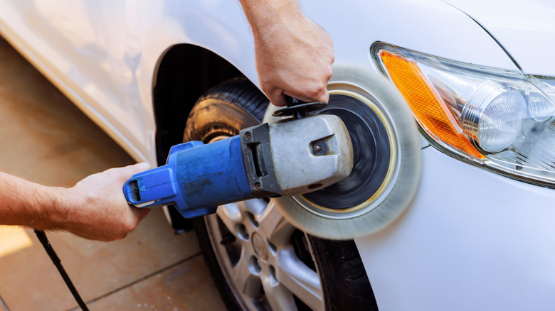 Worker use buffer polisher on white car in driveway