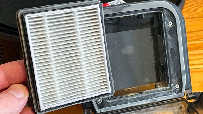 Open dustbin for the Roborock Q7 M5+ with the filter being held in one hand.