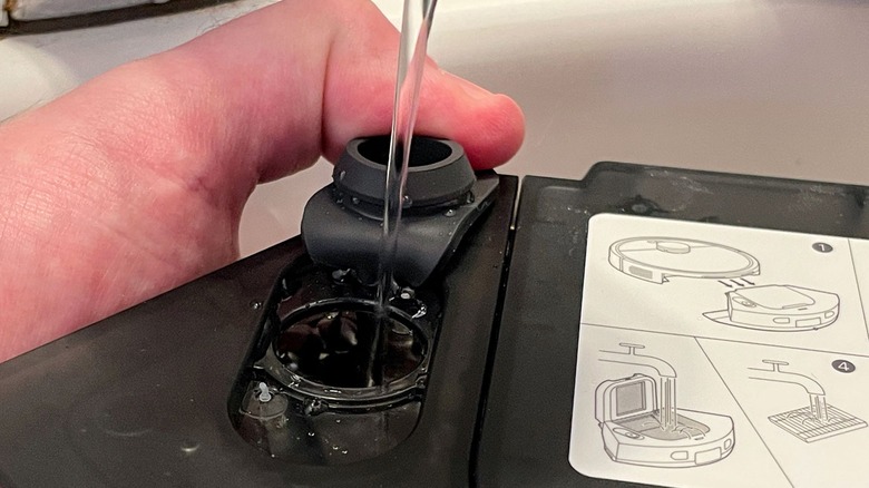 Filling the water tank for the Roborock Q7 M5+ in a sink.