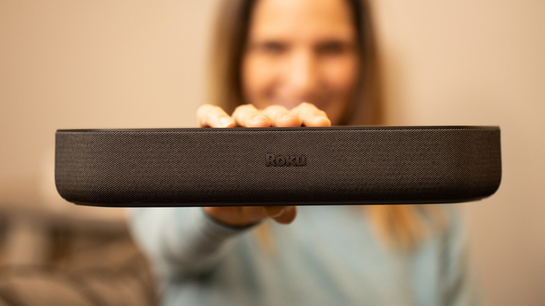 A woman holding a Roku Streambar