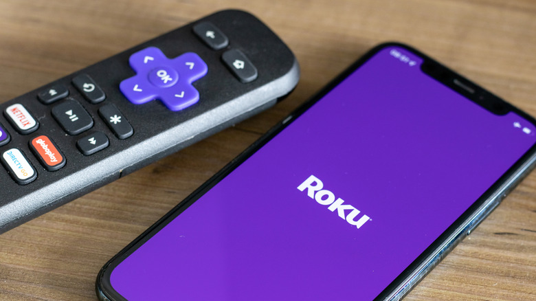 Roku remote next to a smartphone showing the Roku logo
