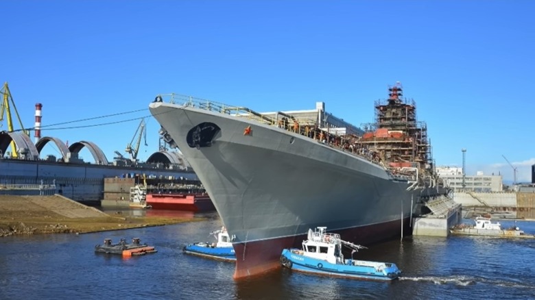 The Admiral Nakhimov being maneuvered by tugs while undergoing refits