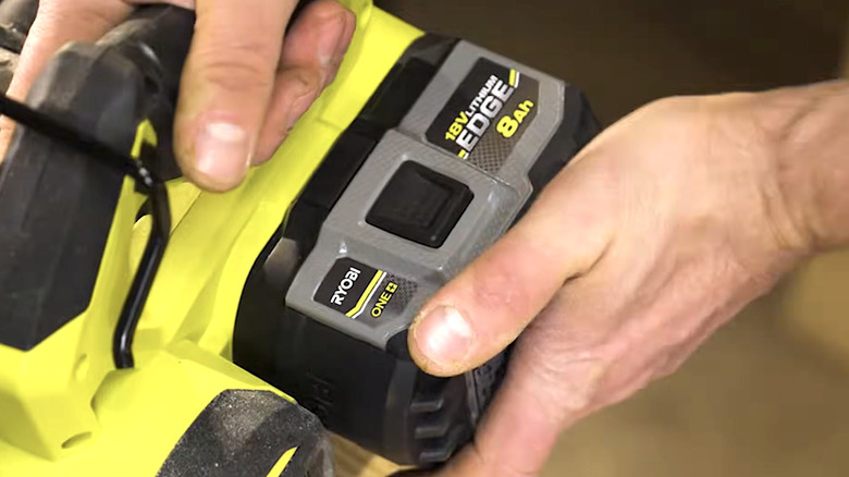 Person installing a One+ 18V Lithium-ion Edge battery pack into a Ryobi tool
