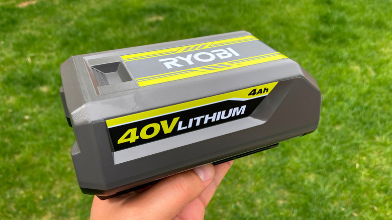 A person holding a 40V Ryobi battery outside.