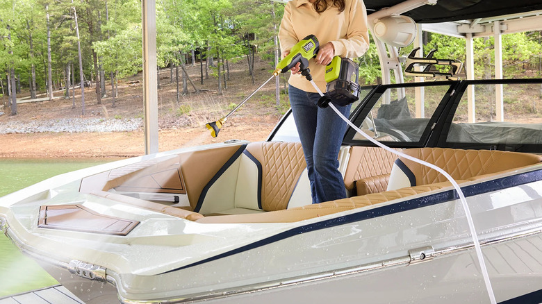 Person standing in a boat and cleaning it with a Ryobi 40V HP power cleaner