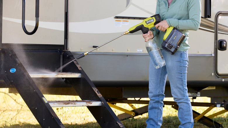 Person cleaning an RV using a Ryobi 40V HP power cleaner with a bottle attached