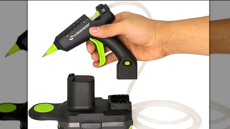 Hand picking up Surebonder glue gun on white background