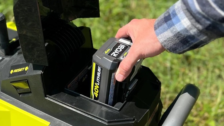 A person inserting a Ryobi battery into a tool
