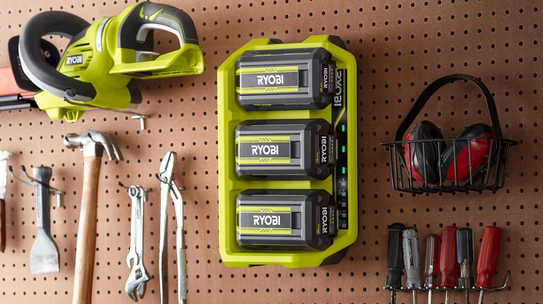 A battery charger mounted on a pegboard with other Ryobi tools