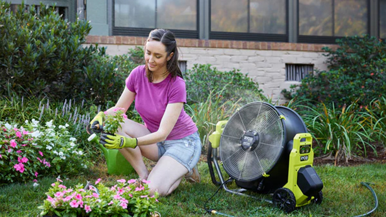 A woman using a Ryobi 40V HP fan in the garden