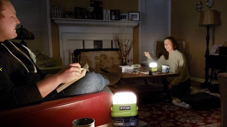 A man and a woman sitting in a dark room using products from Ryobi's Storm Preparation Kit