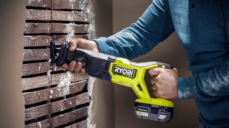 A person using a Ryobi ONE+ HP reciprocating saw indoors.