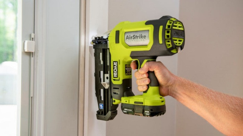 Person using framing nailer on door frame