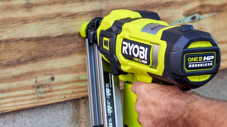 Person using framing nailer on wall