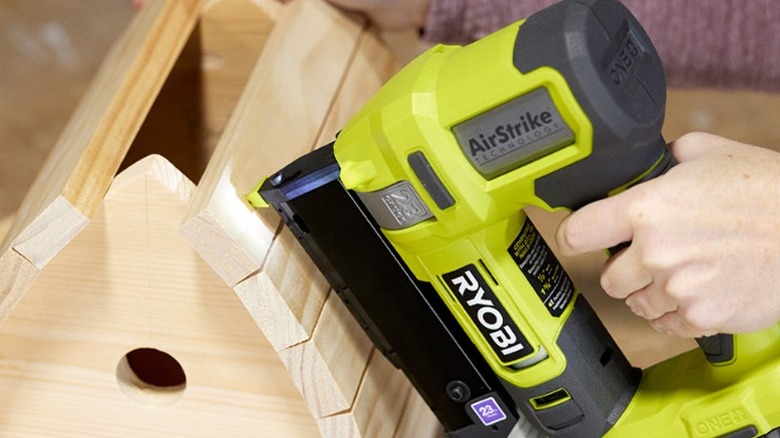 Person using pin nailer on bird house