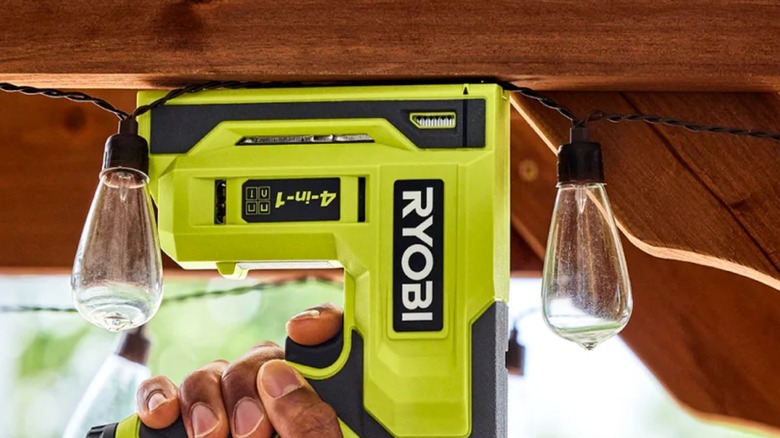 A person putting up lights with a Ryobi USB stapler.