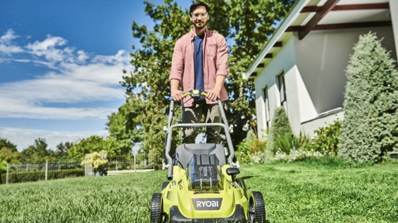 Head-on view of man mowing grass with Ryobi lawnmower