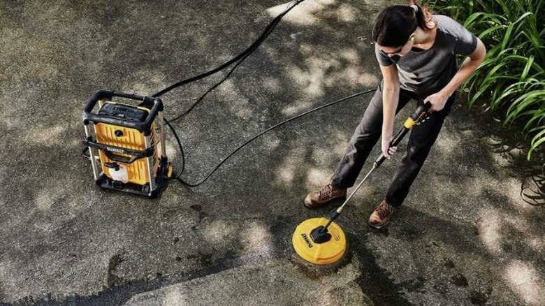 Woman cleaning driveway with DeWalt surface cleaner
