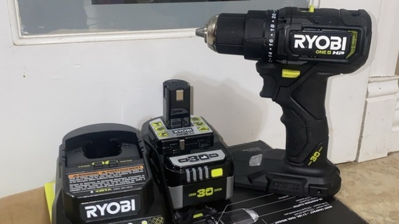 Black Ryobi drill, battery, and charger on top of box