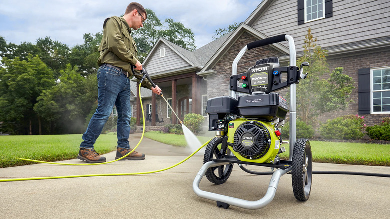 Person using a Ryobi gas pressure washer to clean their driveway