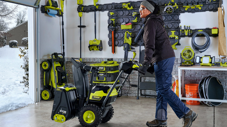 Ryobi battery-powered snow blower being rolled out of a garage