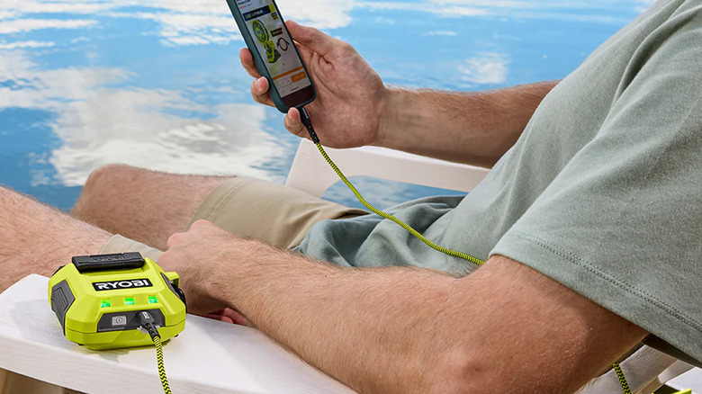 Person charging phone with Ryobi Power Source