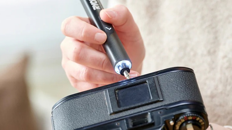 A person fixing a camera with a Ryobi Microtech screwdriver.