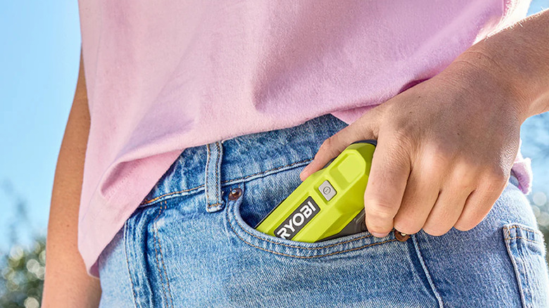 A person putting Ryobi fan into their pants pocket
