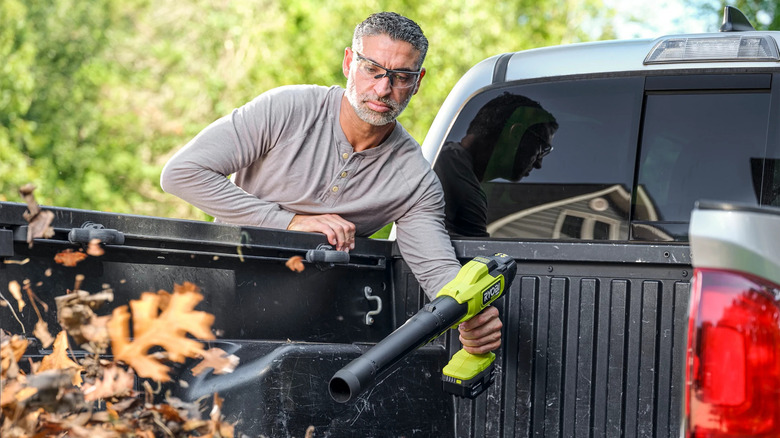 man blowing leaves off truck