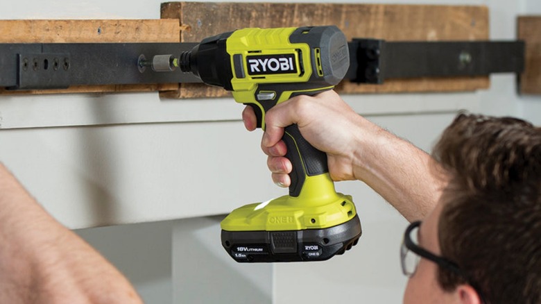 Person using Ryobi drill on barn door bracket