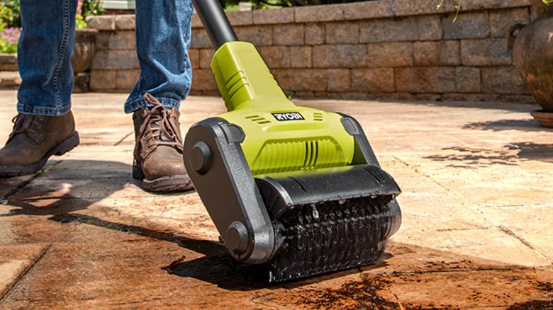A person using a Ryobi patio cleaner on stone.