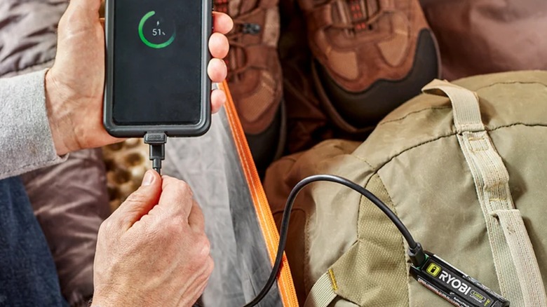 A man charging phone with Ryobi USB Lithium battery
