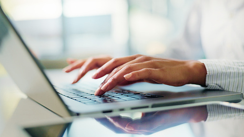 Close up of a woman's hands typing on a laptop