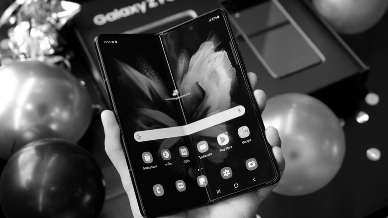 B&W photo of a person holding a folding phone