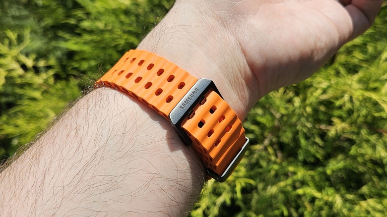 Samsung Galaxy Watch Ultra strapped on a wrist with a green bush in the background