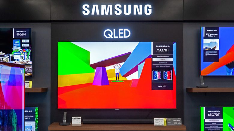 multiple Samsung QLED TVs on display in a retail store