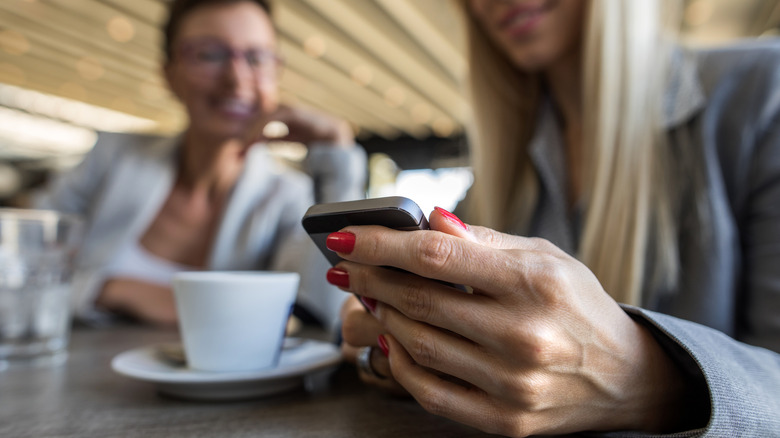 Person using a smartphone in a cafe.