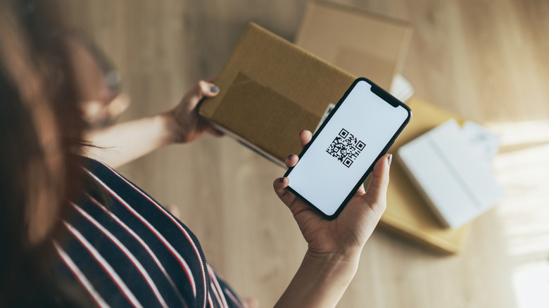 Person holding a phone displaying a QR code