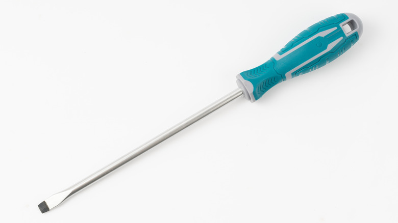 A flathead screwdriver with a teal handle placed on a white surface