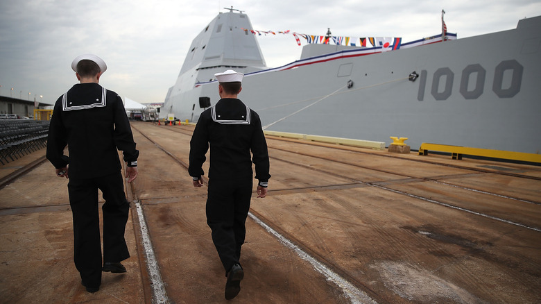 two sailors walking beside the USS Zumwalt in dock