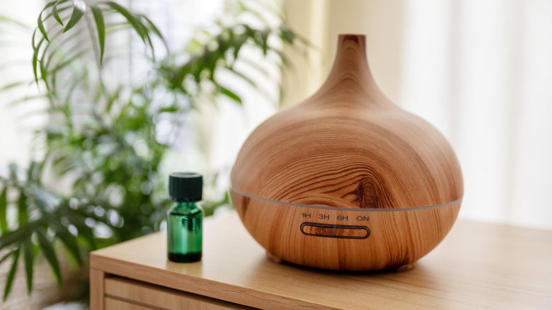 Round wooden oil diffuser next to a green bottle