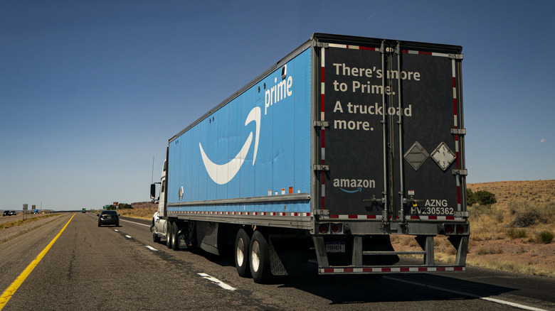 Rear view of Amazon Prime semi truck driving on desert highway.
