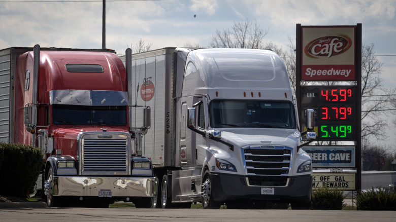 Front view of diesel semi trucks parked in front of Speedway truck stop.