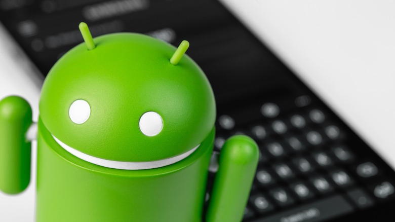 Google Android figure and smartphone with keyboard closeup
