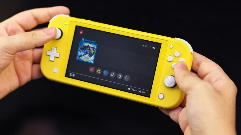 Man holding a Nintendo Switch Lite against a black background.