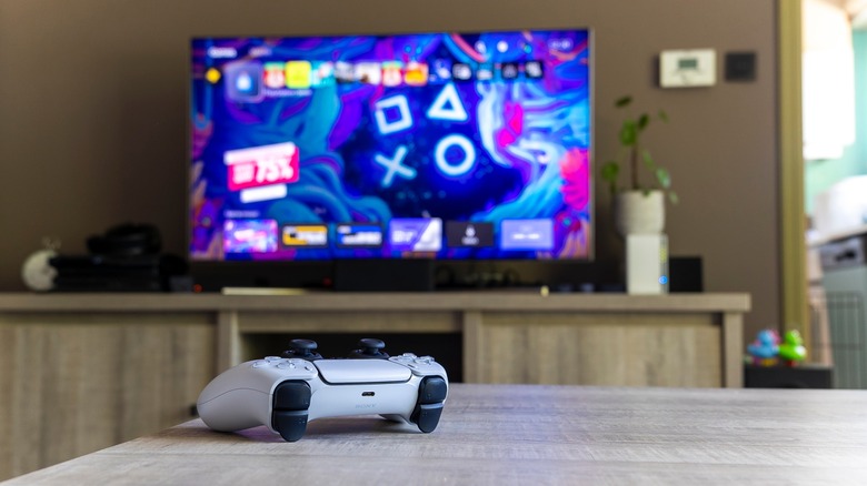 PS5 controller on table with TV in background