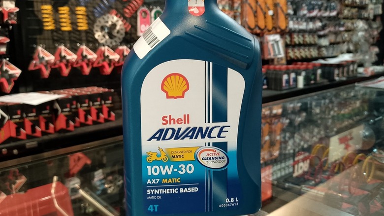 A bottle of Shell Advance motorcycle oil sitting in front of a store's display.